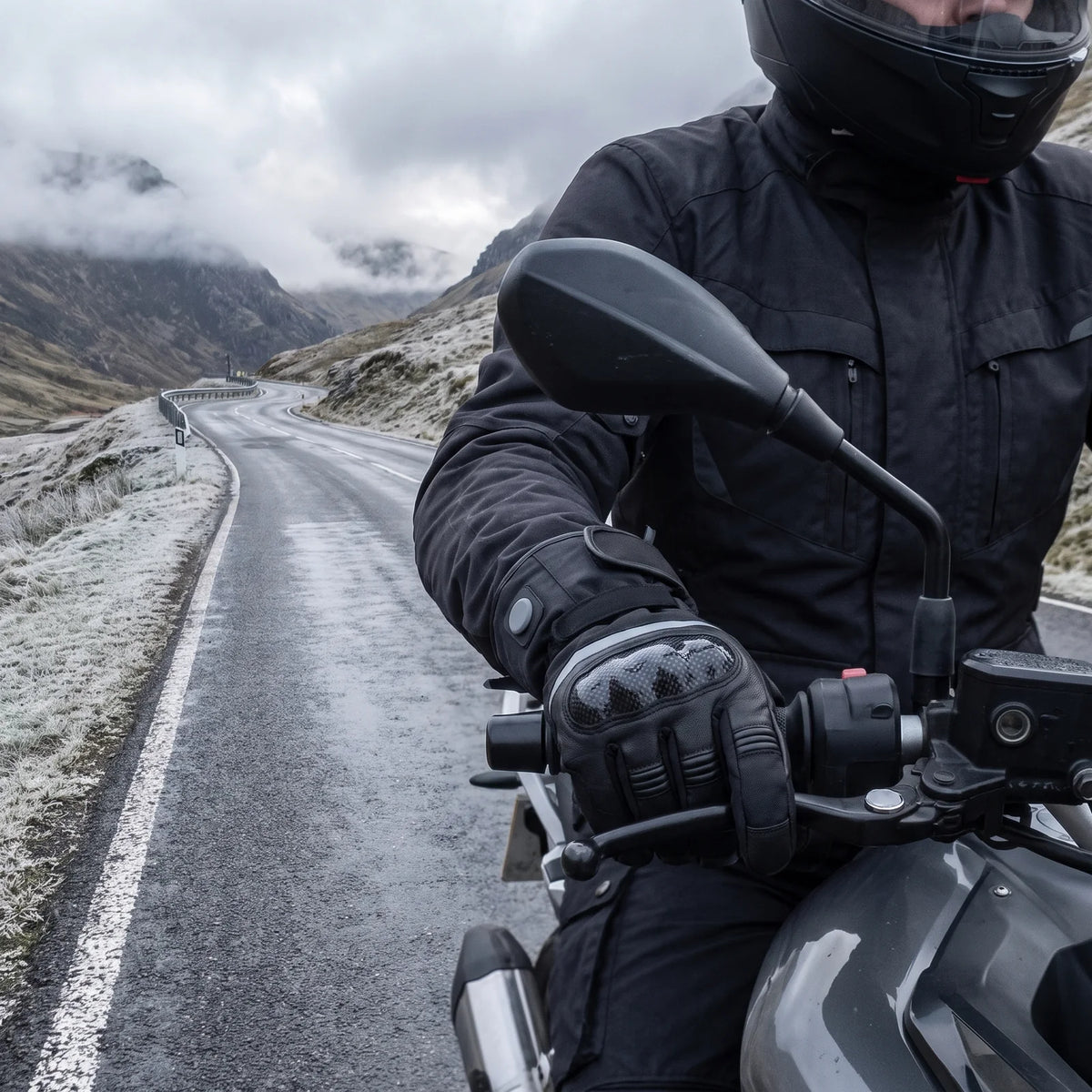 Rider on a cold mountain pass road, hands in heated gloves on the handlebar