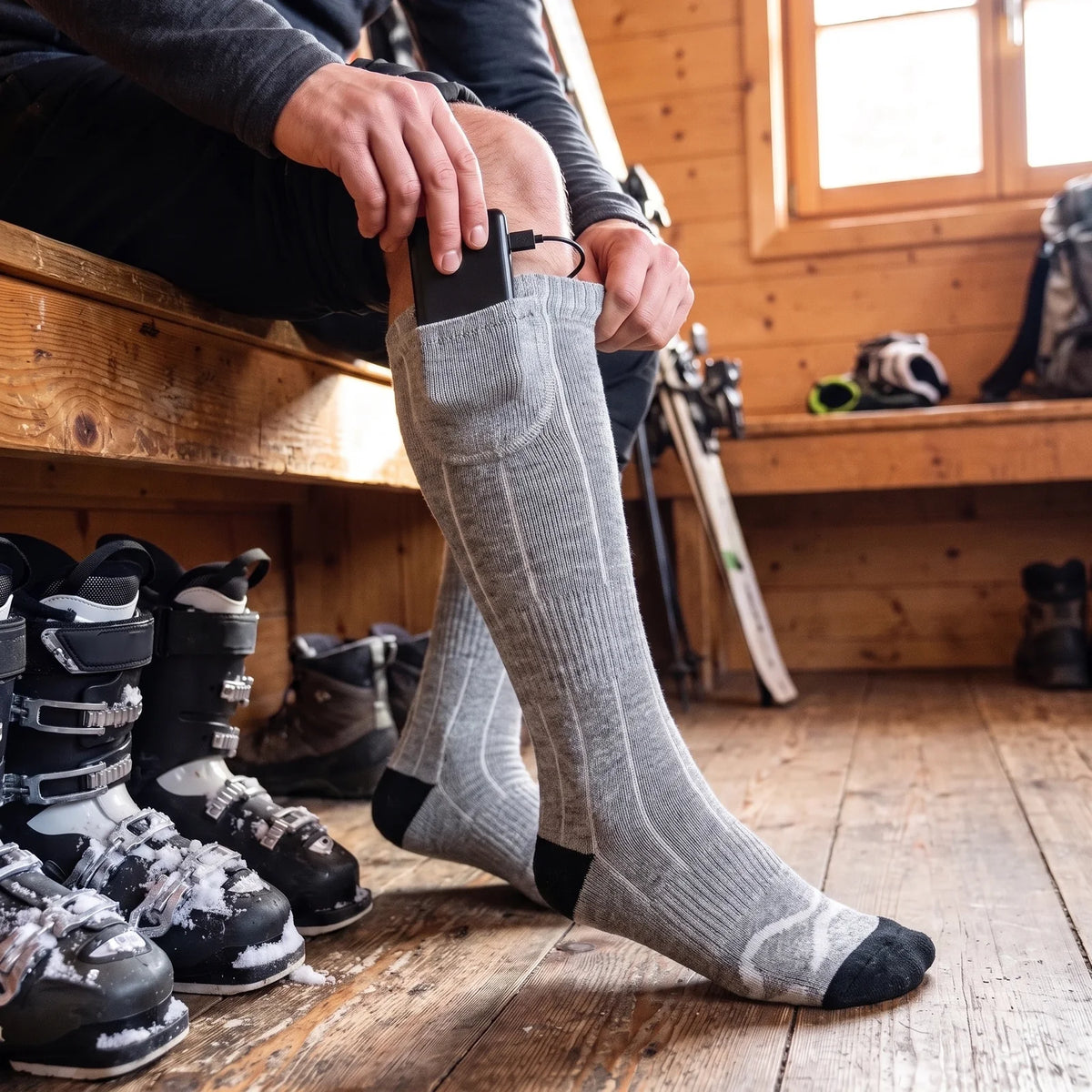 Battery slid into the cuff pocket of a heated knee-high sock, ski boots in a mountain hut