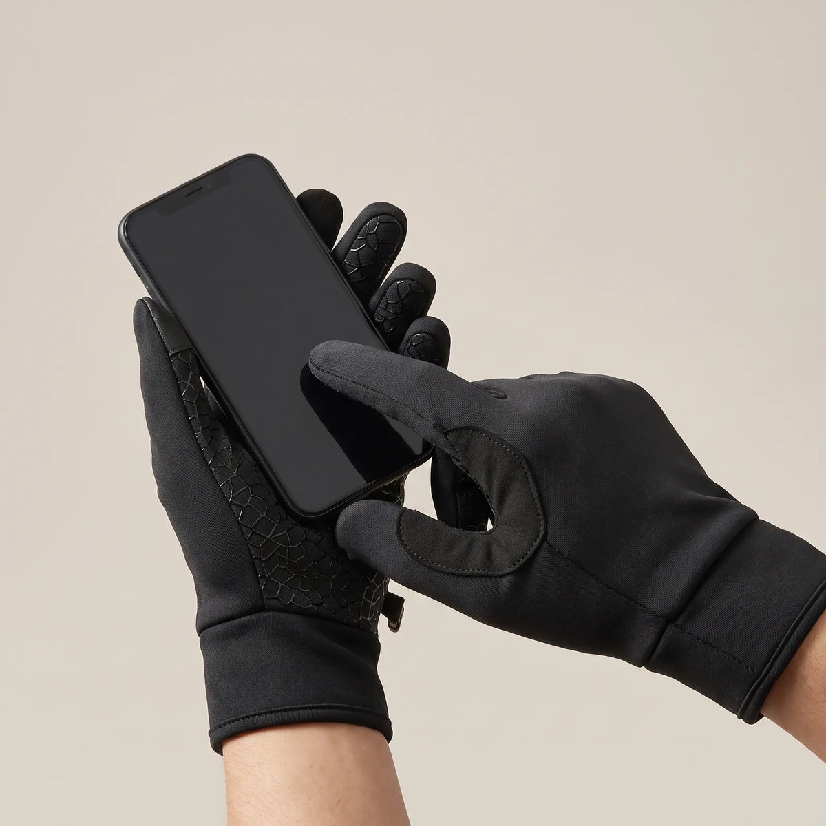 Zeigefinger im Handschuh tippt auf ein Smartphone